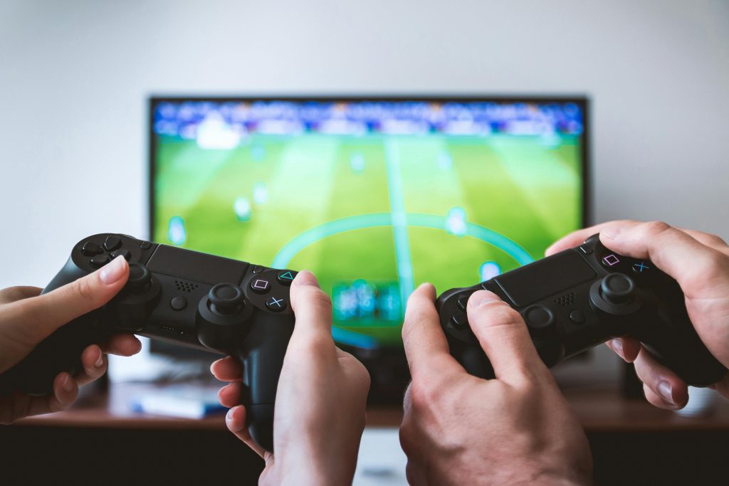 Video Game Devs Worry About Sustainability of Live Services 2 controllers with tv in background