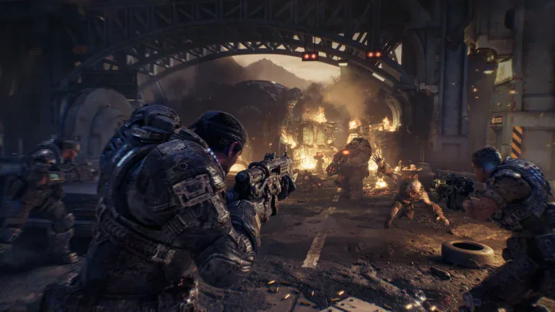 Marcus Fenix and Bravo Squad fight Locust under a burning bridge in Gears of War: E-Day