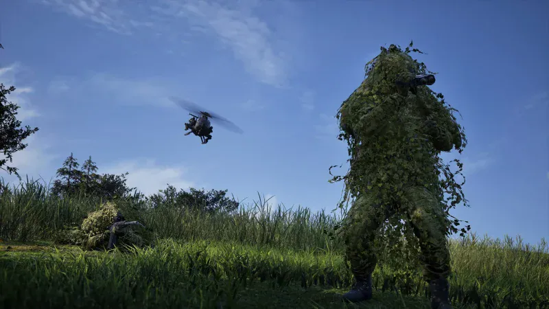 A sniper in a ghillie suit stands in long grass as a helicopter flies overhead in WARDOGS